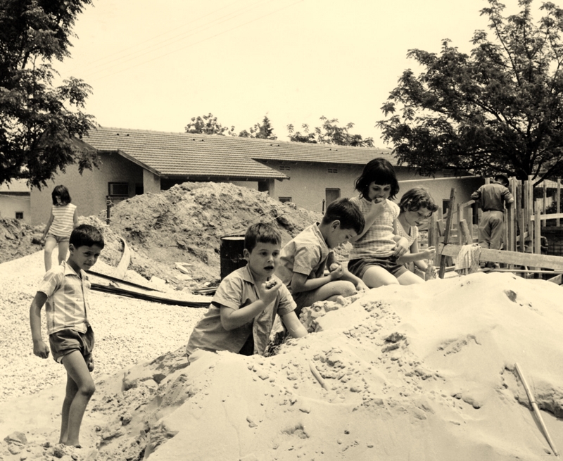 ילדים משחקים בערימות החול שהובאו למטרת בניית המקלטים. התמונה מהארכיון