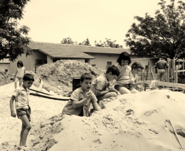 ילדים משחקים בערימות החול שהובאו למטרת בניית המקלטים. צילם: אליהו כהן ז"ל